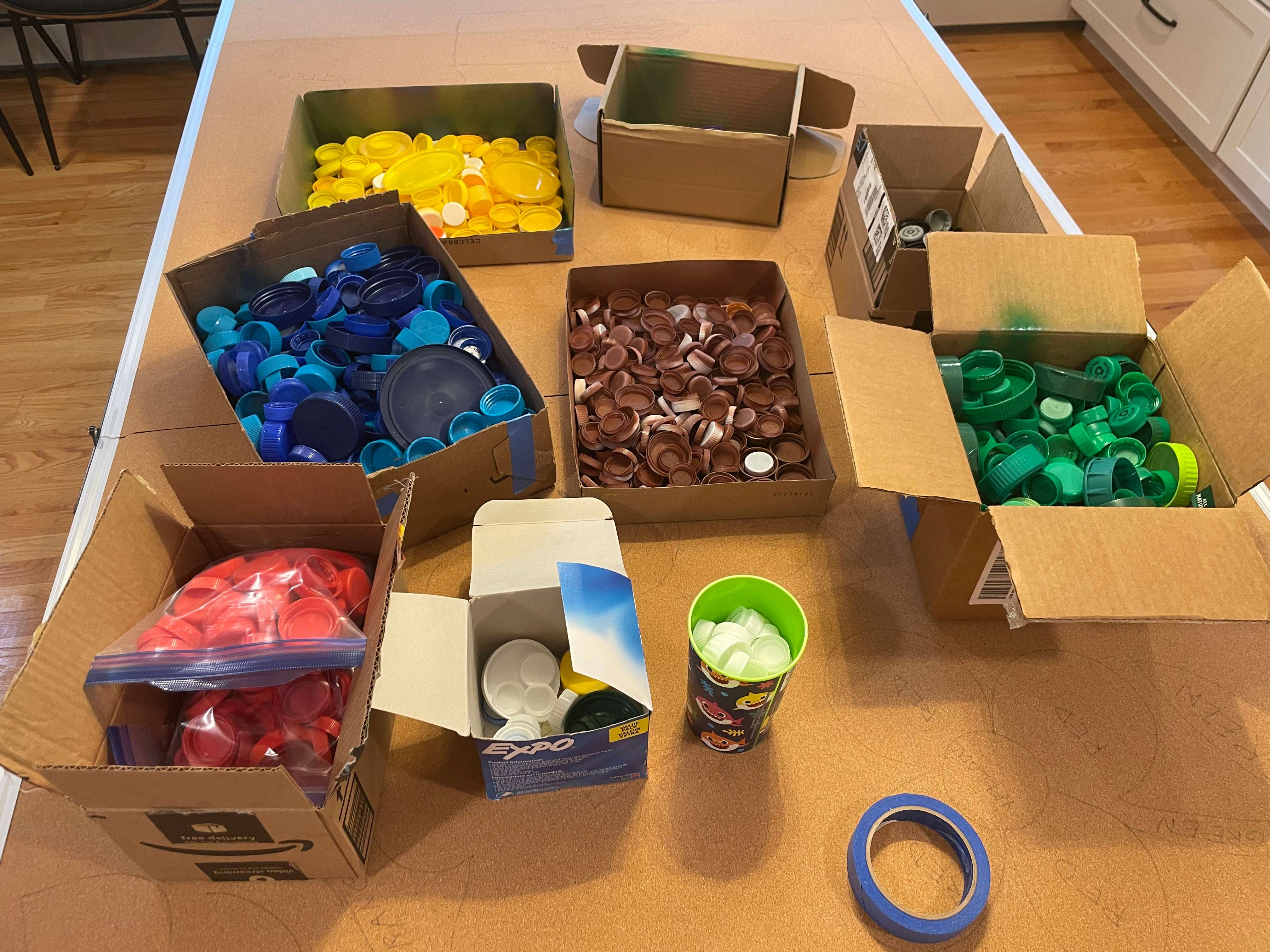 Cardboard boxes filled with bottle caps sorted by color